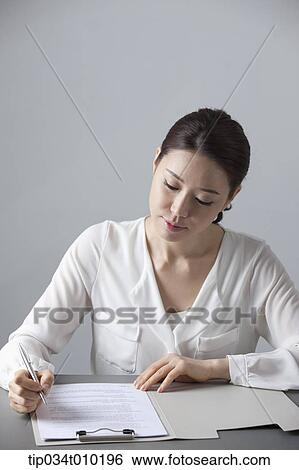 a woman writing something on a folder View Large Photo Image Stock Photograph - a woman writing something on a folder. Fotosearch