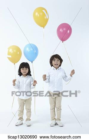 Stock Image - brother and sister holding balloons. Fotosearch