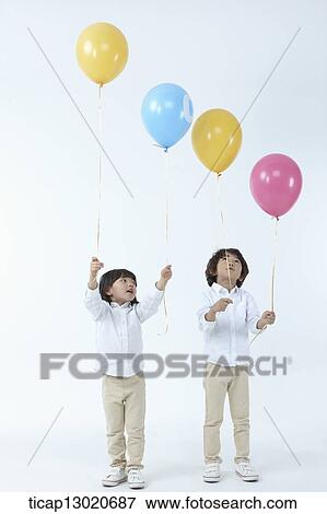 Stock Photo - brother and sister holding balloons. Fotosearch