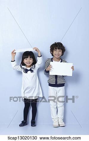 Stock Image - brother and sister holding blank papers. Fotosearch