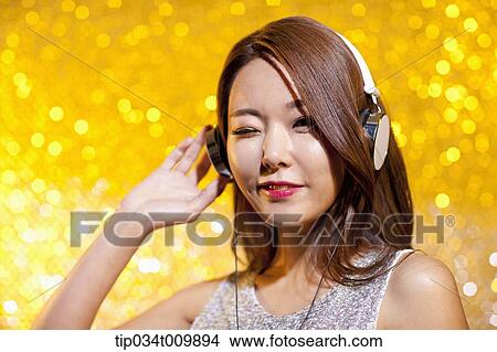 Picture - close up of a woman in fancy dress listening to music with headphone. Fotosearch