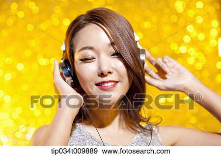 Stock Photo - close up of a woman in fancy dress listening to music with headphone. Fotosearch