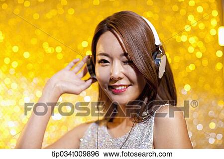 Stock Photograph - close up of a woman in fancy dress listening to music with headphone. Fotosearch