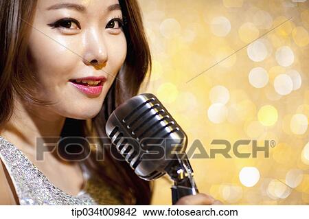 Stock Image - close up of a woman singing with microphone in fancy dress. Fotosearch