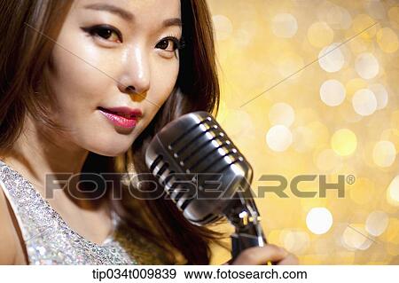 Stock Photo - close up of a woman singing with microphone in fancy dress. Fotosearch