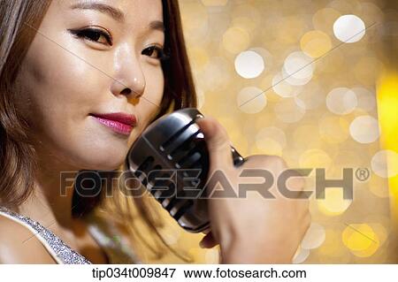 Stock Photo - close up of a woman singing with microphone in fancy dress. Fotosearch