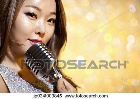 Stock Photography - close up of a woman singing with microphone in fancy dress. Fotosearch