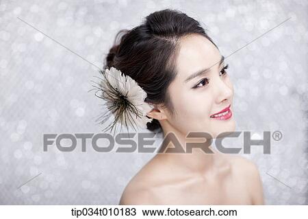 Stock Image - close up of a woman with flower in the head posing gracefully . Fotosearch