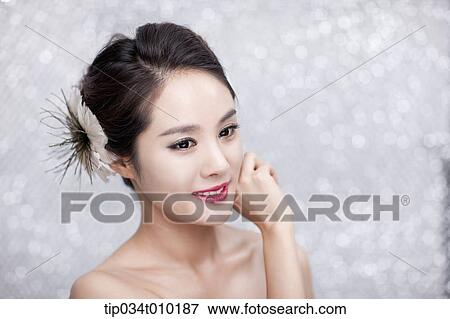 Stock Photo - close up of a woman with flower in the head posing gracefully . Fotosearch