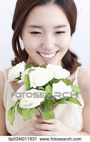 Stock Image - close up shot of a lady holding a bundle of flowers. Fotosearch