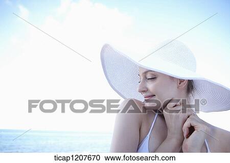 Stock Image - close up shot of a lady in beach hat under the sun. Fotosearch