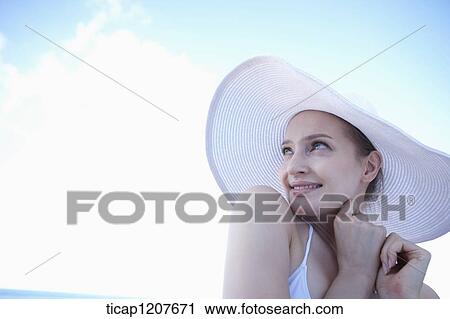 Stock Image - close up shot of a lady in beach hat under the sun. Fotosearch