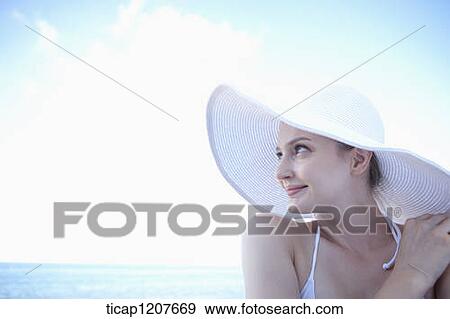 Stock Photo - close up shot of a lady in beach hat under the sun. Fotosearch