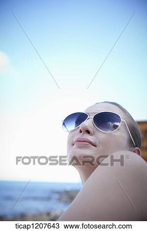 Stock Image - close up shot of a lady in sunglasses under the sun. Fotosearch