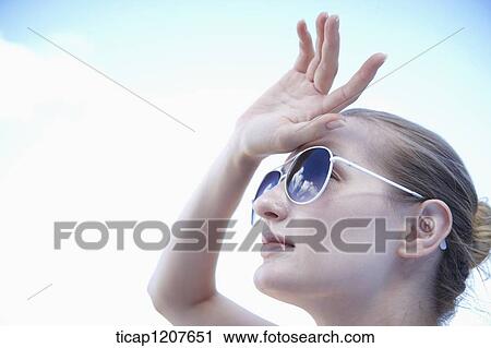 Stock Image - close up shot of a lady in sunglasses under the sun. Fotosearch