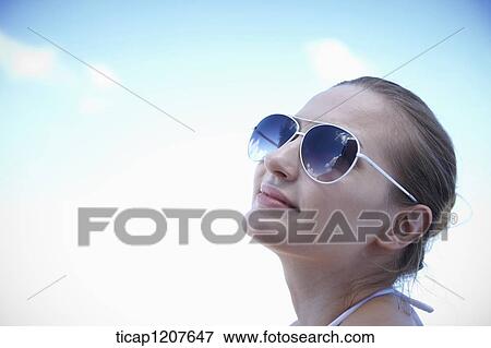 Stock Photo - close up shot of a lady in sunglasses under the sun. Fotosearch