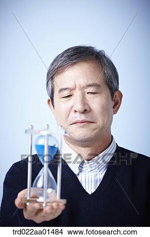 close up shot of middle aged man with sand hourglass View Large Photo Image Picture - close up shot of middle aged man with sand hourglass. Fotosearch