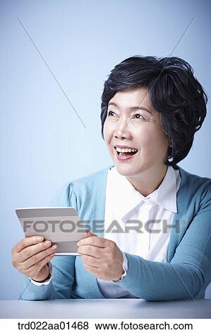 close up shot of middle aged woman happily opening bankbook View Large Photo Image Stock Photo - close up shot of middle aged woman happily opening bankbook. Fotosearch