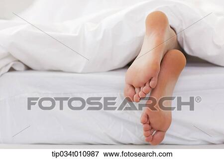 Stock Photo - feet of a woman on the bed. Fotosearch