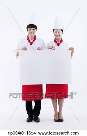 Picture - female and male cook in red apron holding empty board. Fotosearch