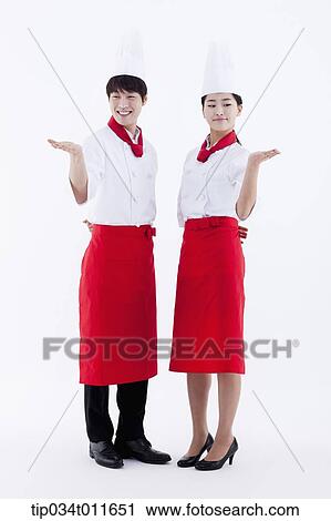 Stock Image - female and male cook in red apron posing. Fotosearch
