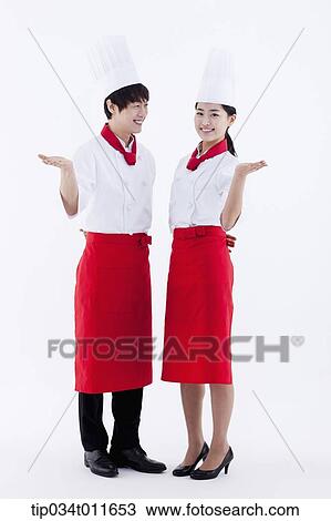 Stock Image - female and male cook in red apron posing. Fotosearch