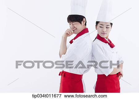 Stock Photo - female and male cook in red apron posing while standing back to back. Fotosearch