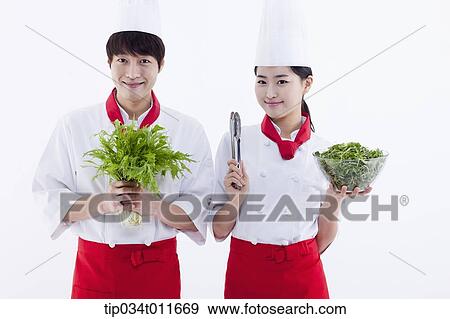 Stock Photo - female and male cook in red apron with posing with salad. Fotosearch