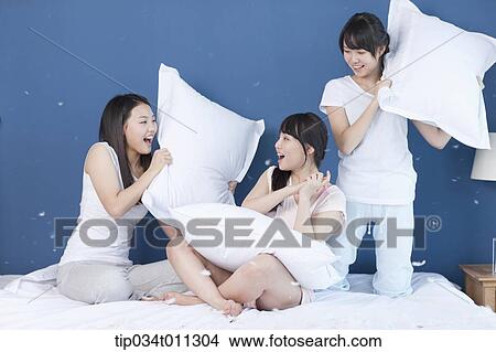 Picture - ladies having a pillow fight. Fotosearch