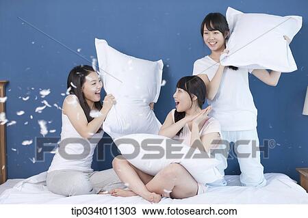 Stock Image - ladies having a pillow fight. Fotosearch