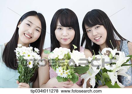 ladies holding white flowers on a couch View Large Photo Image Stock Photo - ladies holding white flowers on a couch. Fotosearch