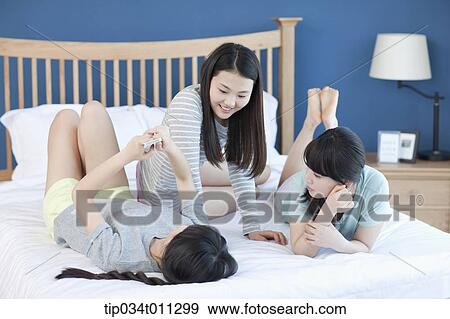 Stock Photo - ladies playing on a bed. Fotosearch