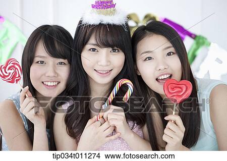Picture - ladies posing with lollipops in the party. Fotosearch