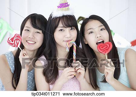 Stock Image - ladies posing with lollipops in the party. Fotosearch