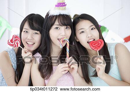 Stock Image - ladies posing with lollipops in the party. Fotosearch