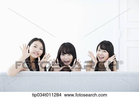 Picture - ladies sitting on a couch posing at camera. Fotosearch