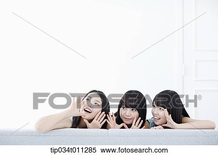 Stock Photography - ladies sitting on a couch posing at camera. Fotosearch