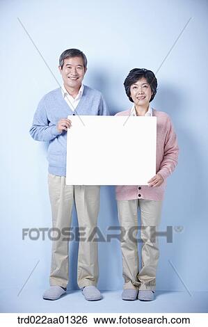 Stock Photograph - middle aged couple holding blank board. Fotosearch