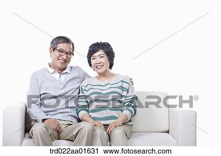 Stock Image - middle aged couple sitting on a couch. Fotosearch