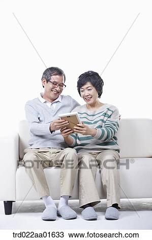 middle aged couple sitting on a couch with family photo album View Large Photo Image Stock Image - middle aged couple sitting on a couch with family photo album. Fotosearch