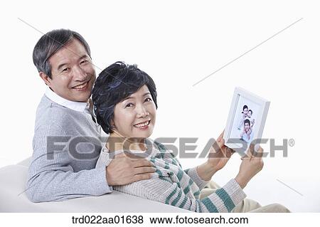 middle aged couple sitting on a couch with family photo album View Large Photo Image Stock Photo - middle aged couple sitting on a couch with family photo album. Fotosearch