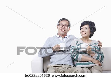 middle aged couple sitting on a couch drinking coffee View Large Photo Image Stock Photograph - middle aged couple sitting on a couch drinking coffee. Fotosearch