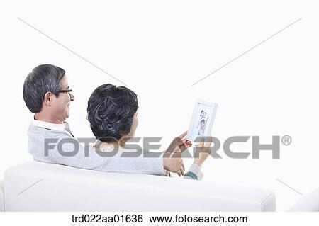 middle aged couple sitting on a couch with family photo album View Large Photo Image Stock Photograph - middle aged couple sitting on a couch with family photo album. Fotosearch
