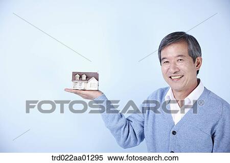 middle aged man holding a mini house on his hand View Large Photo Image Stock Photography - middle aged man holding a mini house on his hand. Fotosearch