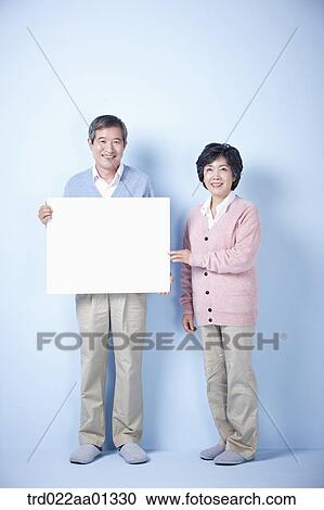 middle aged man holding blank board and woman pointing View Large Photo Image Stock Image - middle aged man holding blank board and woman pointing. Fotosearch