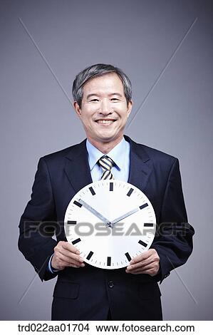 middle aged man in a business suit holding a clock View Large Photo Image Picture - middle aged man in a business suit holding a clock. Fotosearch