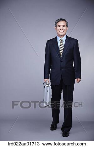 middle aged man in a business suit holding a suitcase View Large Photo Image Stock Image - middle aged man in a business suit holding a suitcase. Fotosearch