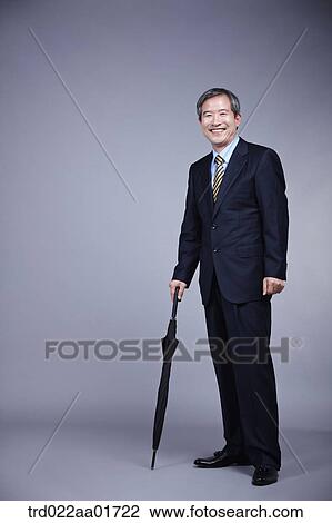 middle aged man in a business suit holding an umbrella View Large Photo Image Stock Image - middle aged man in a business suit holding an umbrella. Fotosearch