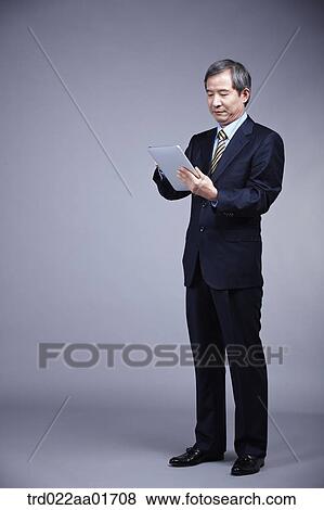 Stock Photo - middle aged man in a business suit using tablet PC. Fotosearch
