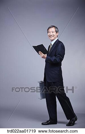 middle aged man in a business suit holding a suitcase View Large Photo Image Stock Photo - middle aged man in a business suit holding a suitcase. Fotosearch